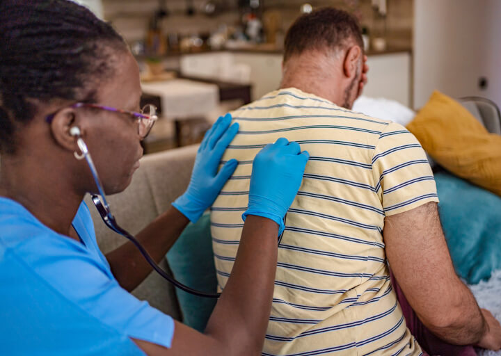 A caregiver checks the health of a sitting patient.